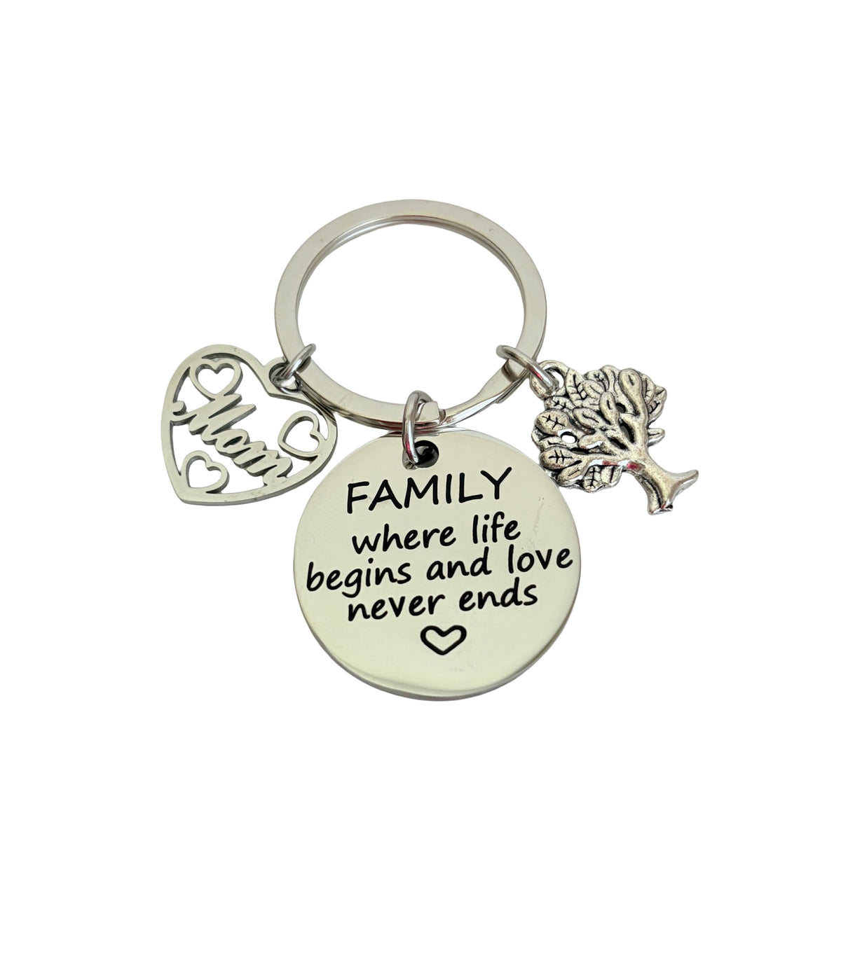 Keychain with heart-shaped charm, round tag with text, and tree charm on a white background