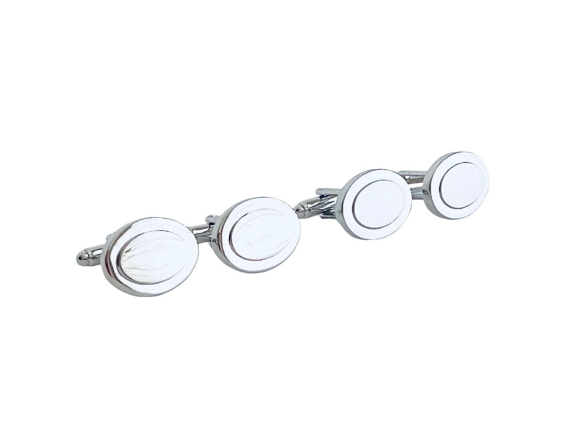 A set of four oval cufflinks with a polished silver-tone metal frame and white inlaid centers, arranged diagonally on a plain white background.