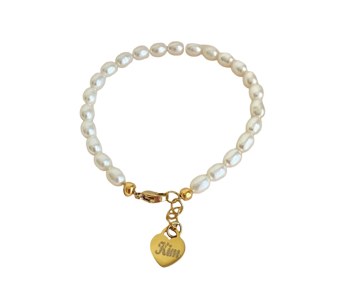A freshwater pearl bracelet with irregular white pearls and gold-toned hardware, featuring a small gold heart charm engraved with the name 'Kim'.