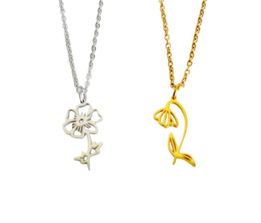 Two flower-shaped pendant necklaces on a plain white background, one in silver and one in gold. The silver pendant is a five-petal flower outline, and the gold pendant is a tulip flower with stem and leaf outline.