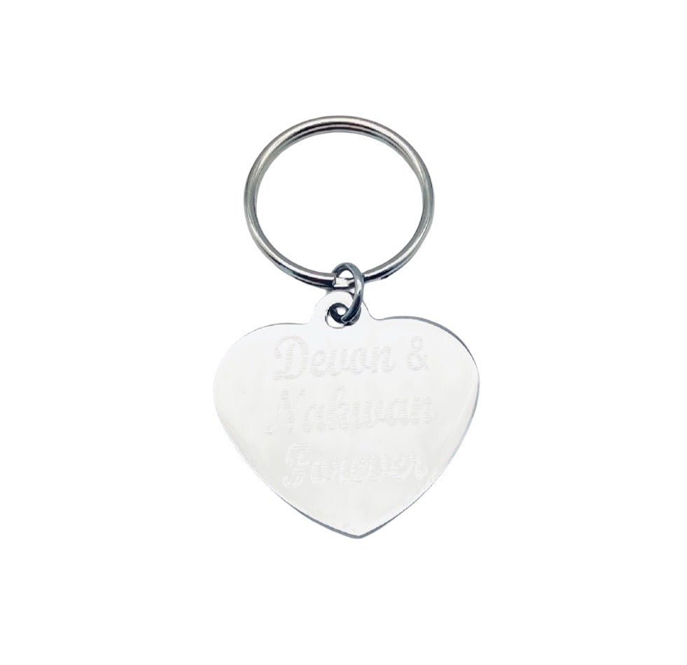 A silver heart-shaped metal keychain with engraved text reading 'Devon & Nakwan Forever' on a plain white background.