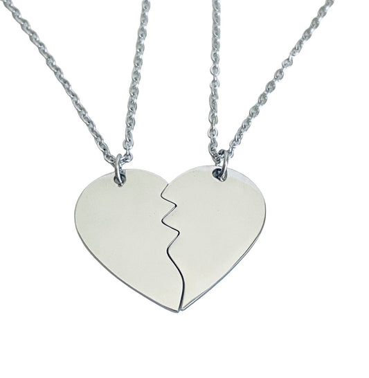 Two matching silver chain necklaces with heart-shaped pendant halves that fit together to form one heart, shown on a plain white background.