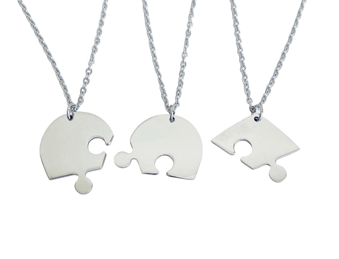 Three silver puzzle-piece necklaces on chains, displayed against a plain white background.