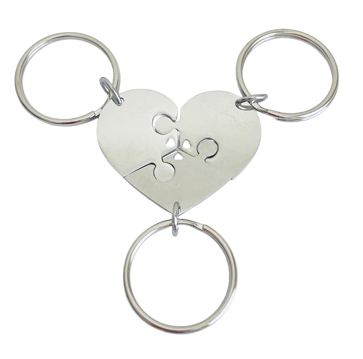 A silver-colored metal keychain featuring a heart-shaped centerpiece with a jigsaw puzzle cutout, three interlocking puzzle pieces, and three attached key rings on a plain white background.