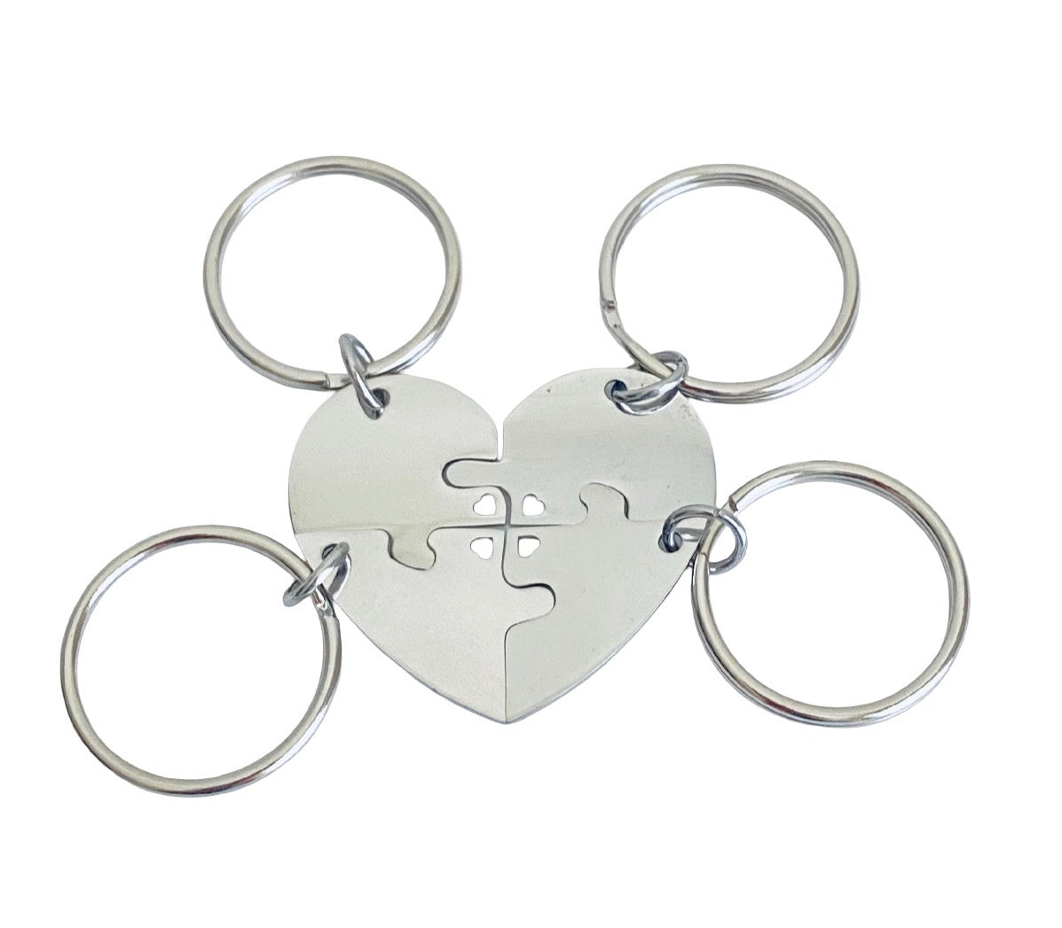 Four-piece silver metal heart jigsaw puzzle keychain with four attached split key rings on a white background.
