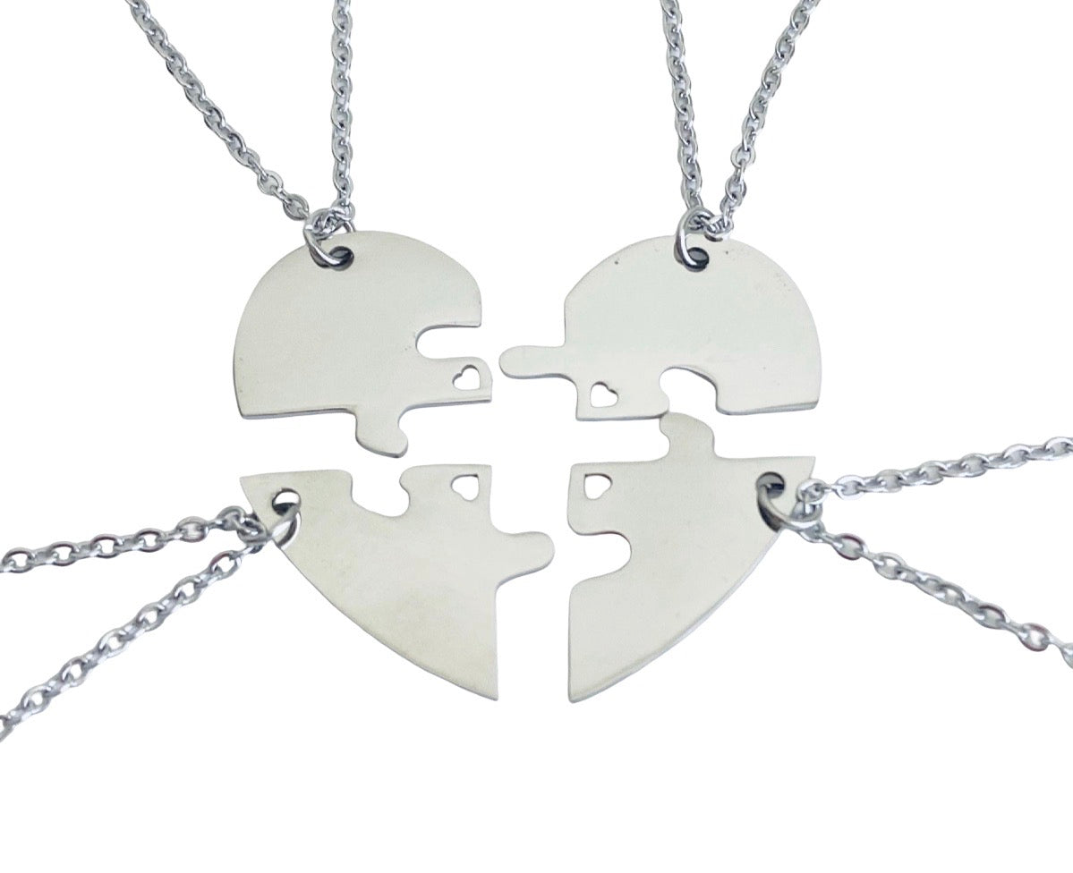 Four silver puzzle heart pendant necklaces arranged to form a single heart shape on a white background.