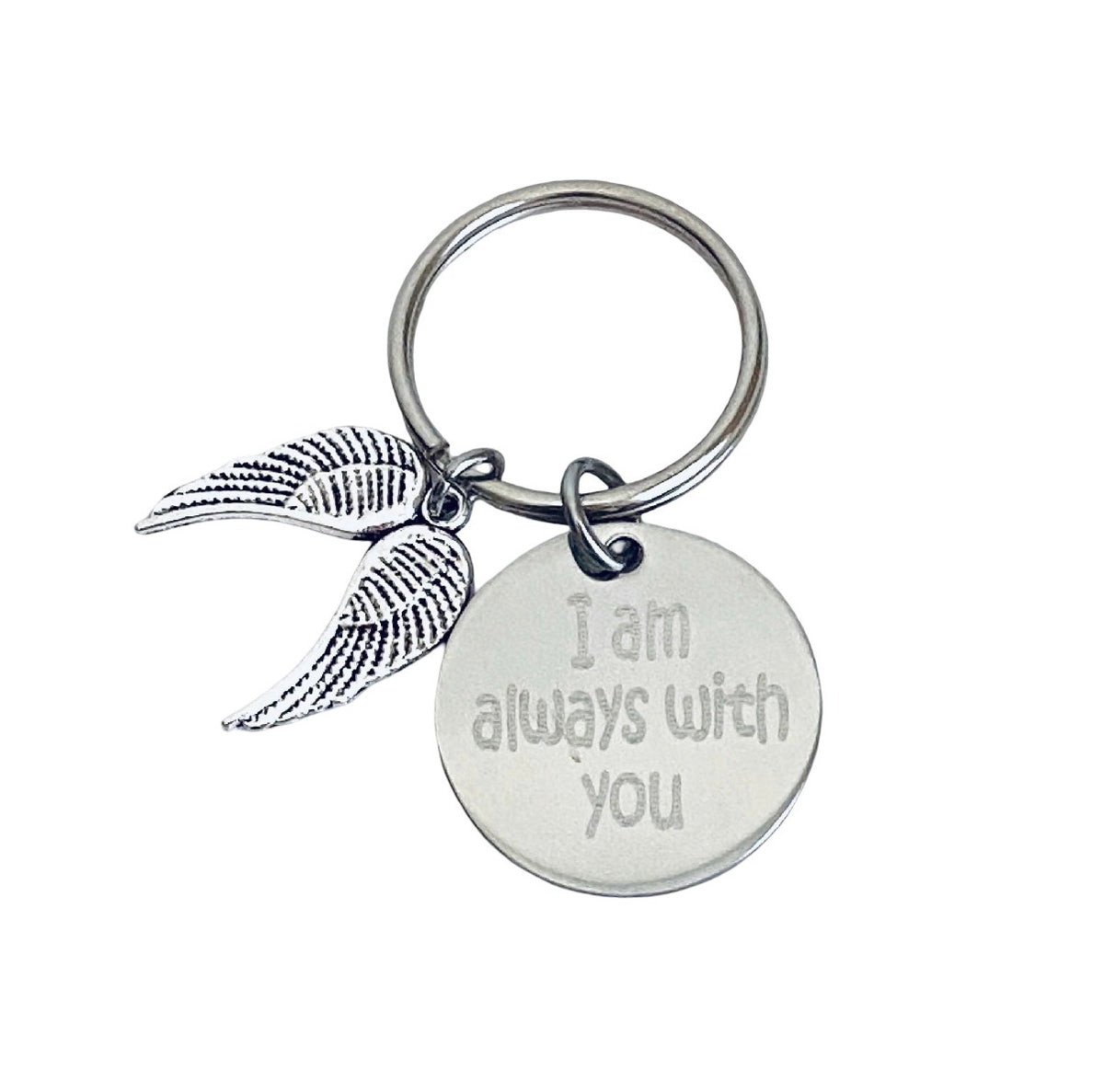 A silver-toned metal keychain featuring a round engraved disc with the phrase 'I am always with you' and a dangling wing charm, shown on a plain white background.