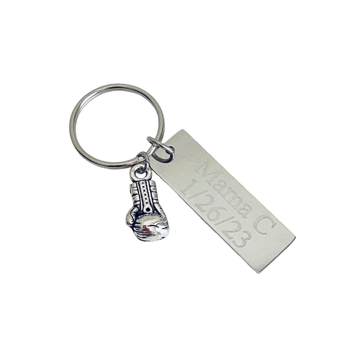 A silver metal keychain featuring a rectangular engraved tag with the text 'Mama C 1/26/23' and a small guitar-shaped charm, shown on a plain white background.
