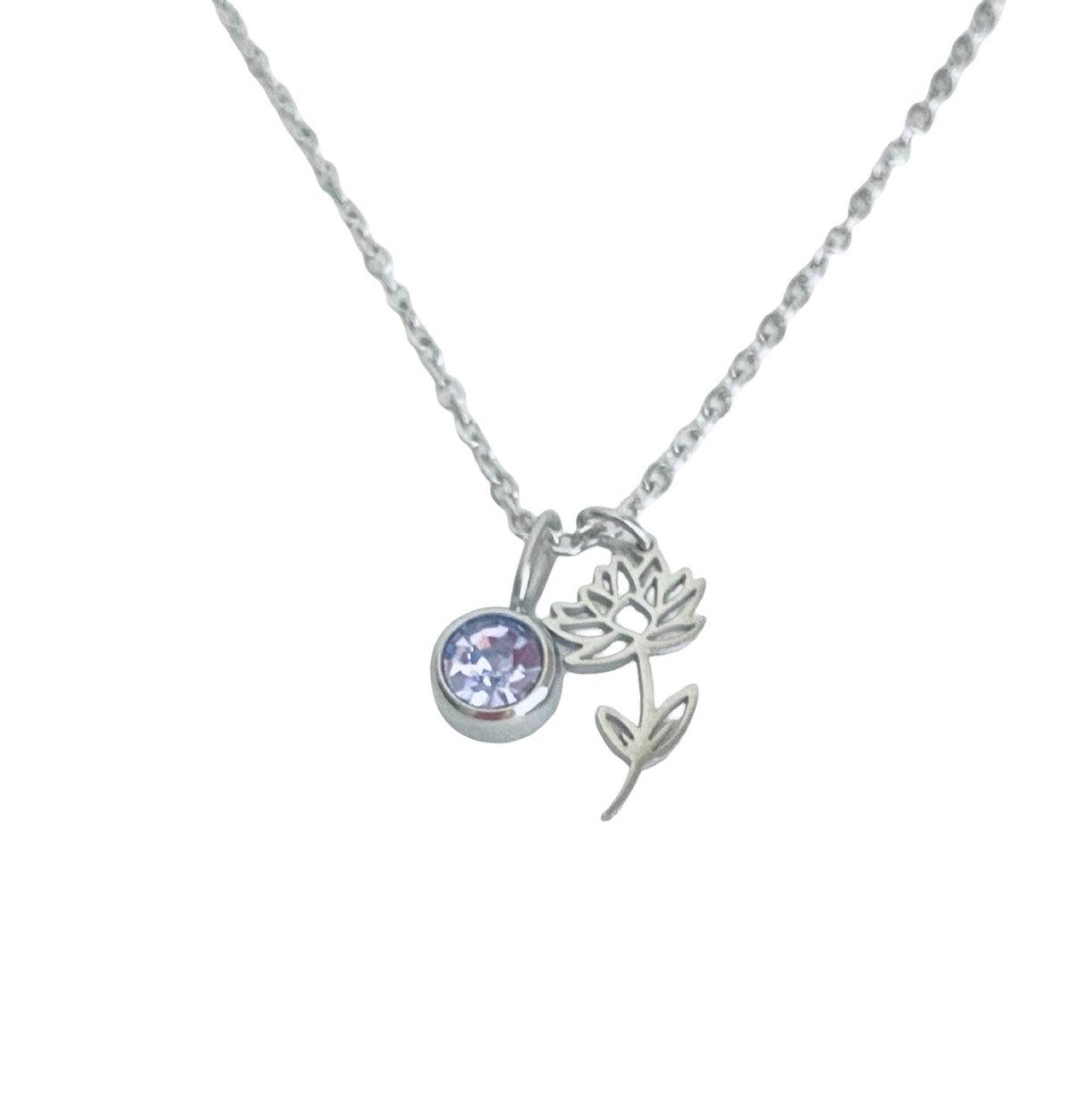 A silver chain necklace featuring a small flower charm and a round bezel-set light purple gemstone pendant, shown against a plain white background.