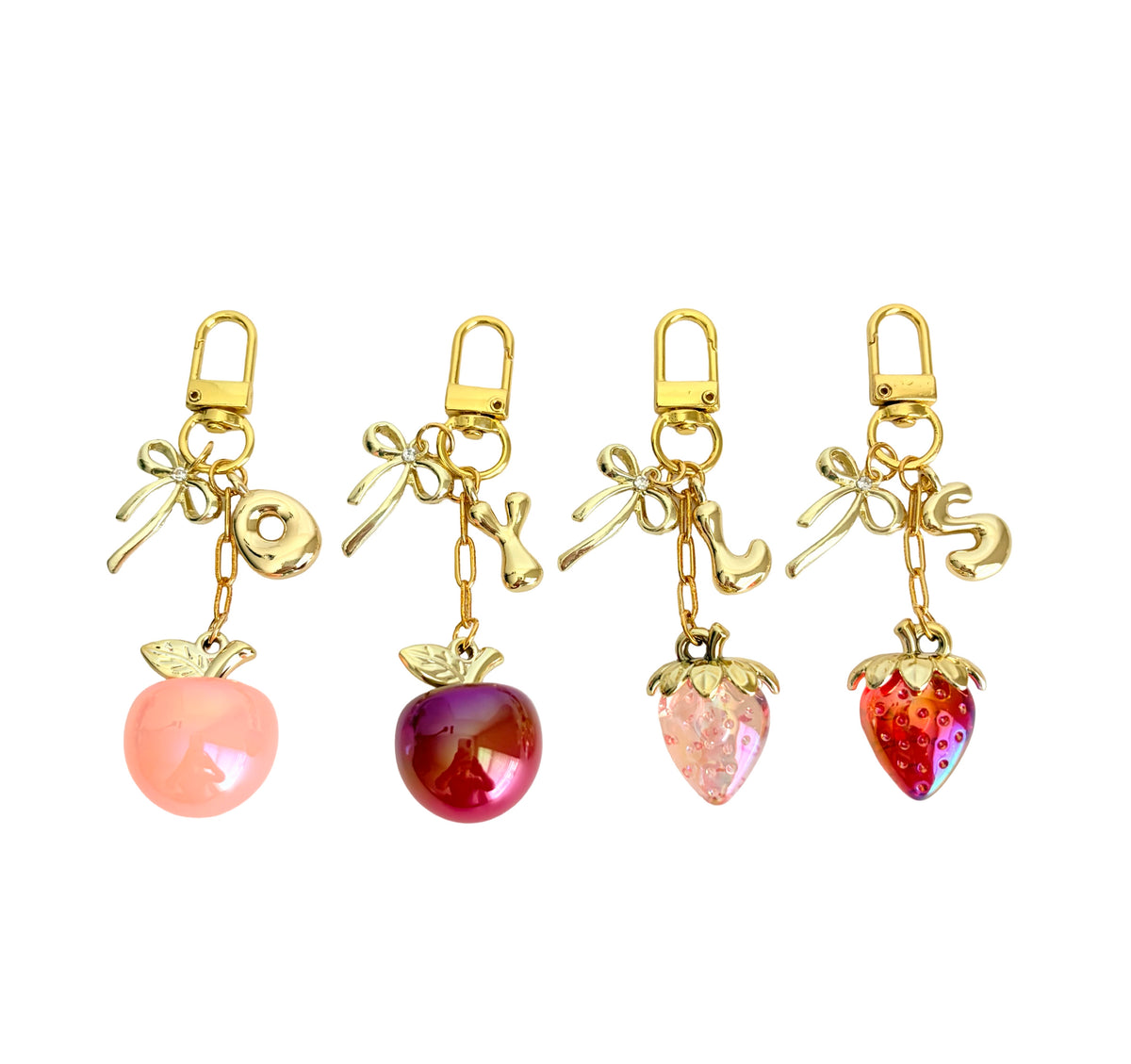 Set of four fruit-shaped keychains with gold accents on a white background