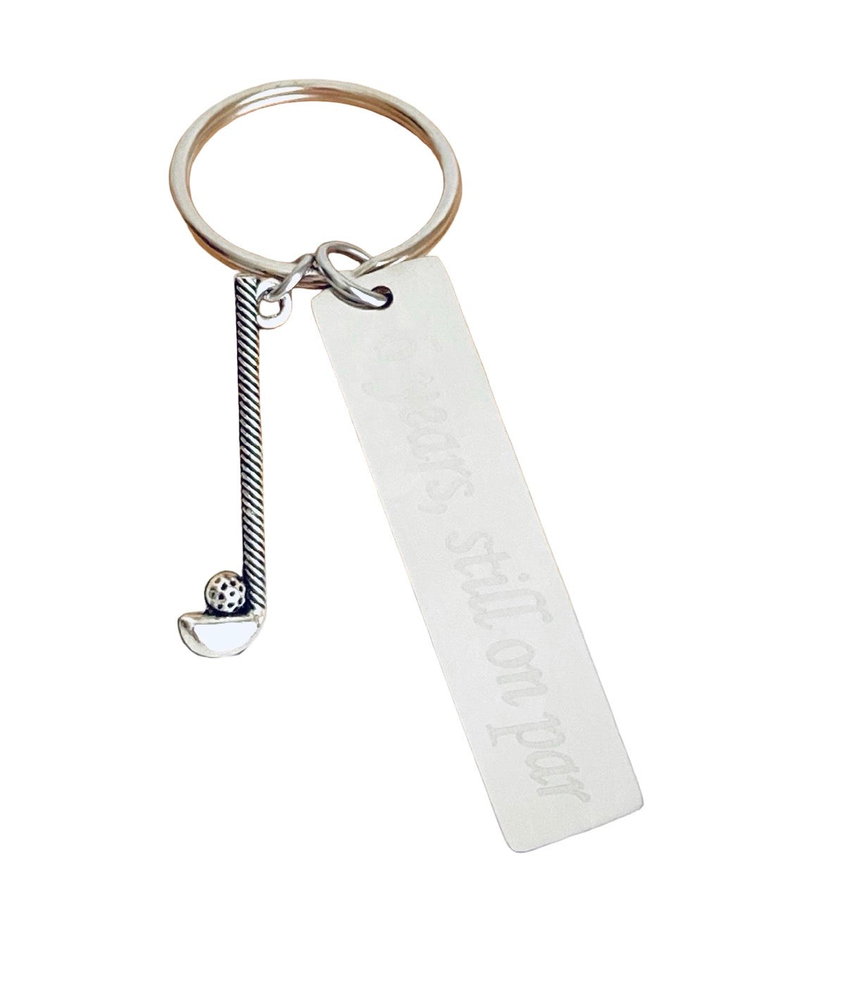 A silver-toned metal keychain featuring a round split ring, a twisted rope charm with a small ball accent, and a blank rectangular tag engraved with the phrase 'your smile on par'.