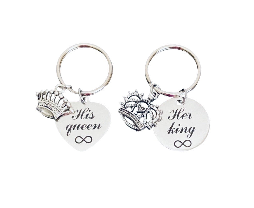 Two silver keychains on a plain white background. One keychain has a crown charm and a heart-shaped charm engraved with 'His queen' and an infinity symbol.