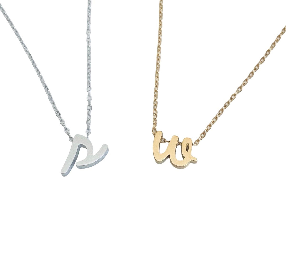 Two minimalist initial necklaces on a white background, one in silver with a lowercase 'p' pendant and one in gold with a lowercase 'w' pendant, both on delicate chains.