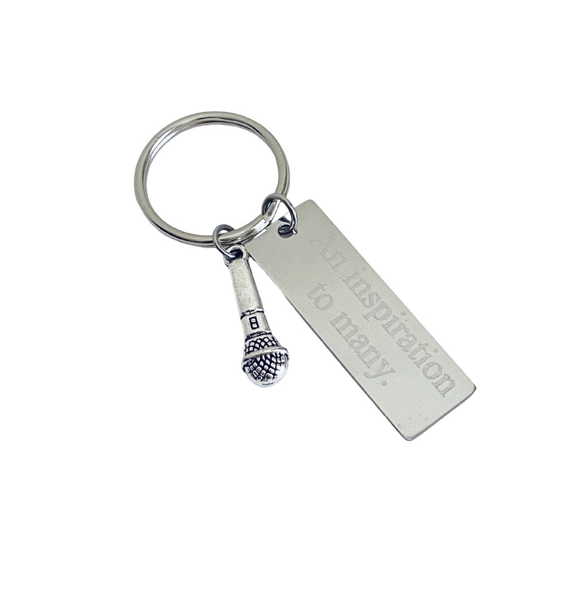 A silver metal keychain featuring a rectangular engraved tag that reads 'an inspiration to many.' and a small Eiffel Tower charm, shown on a plain white background.