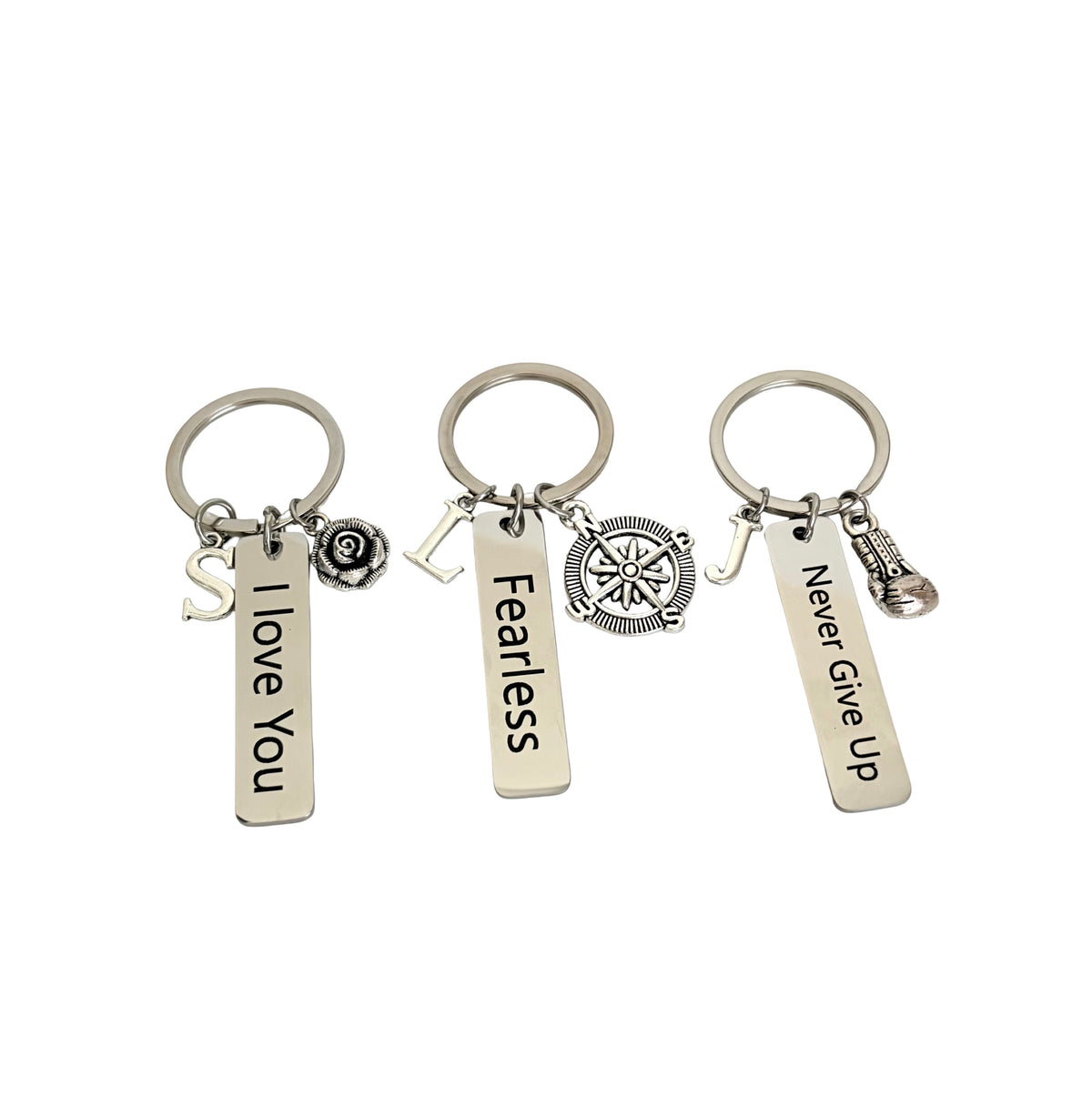 Three silver keychains with motivational phrases on a white background