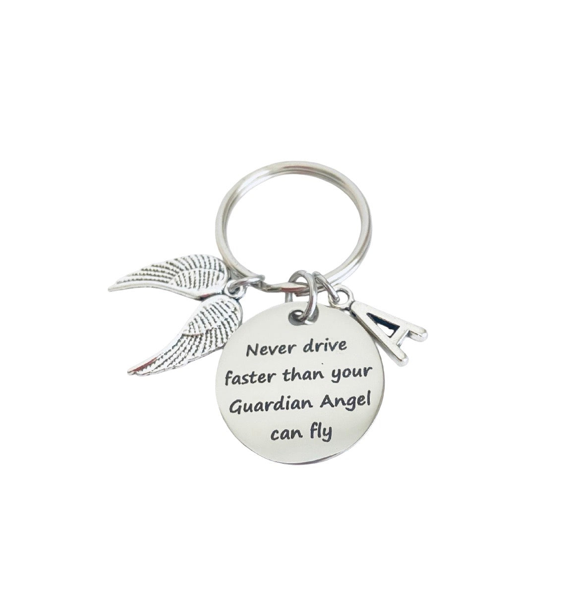 A silver-toned metal keychain featuring a round engraved disc with the phrase 'Never drive faster than your Guardian Angel can fly,' a wing charm, and a small car key charm, shown on a plain white background.