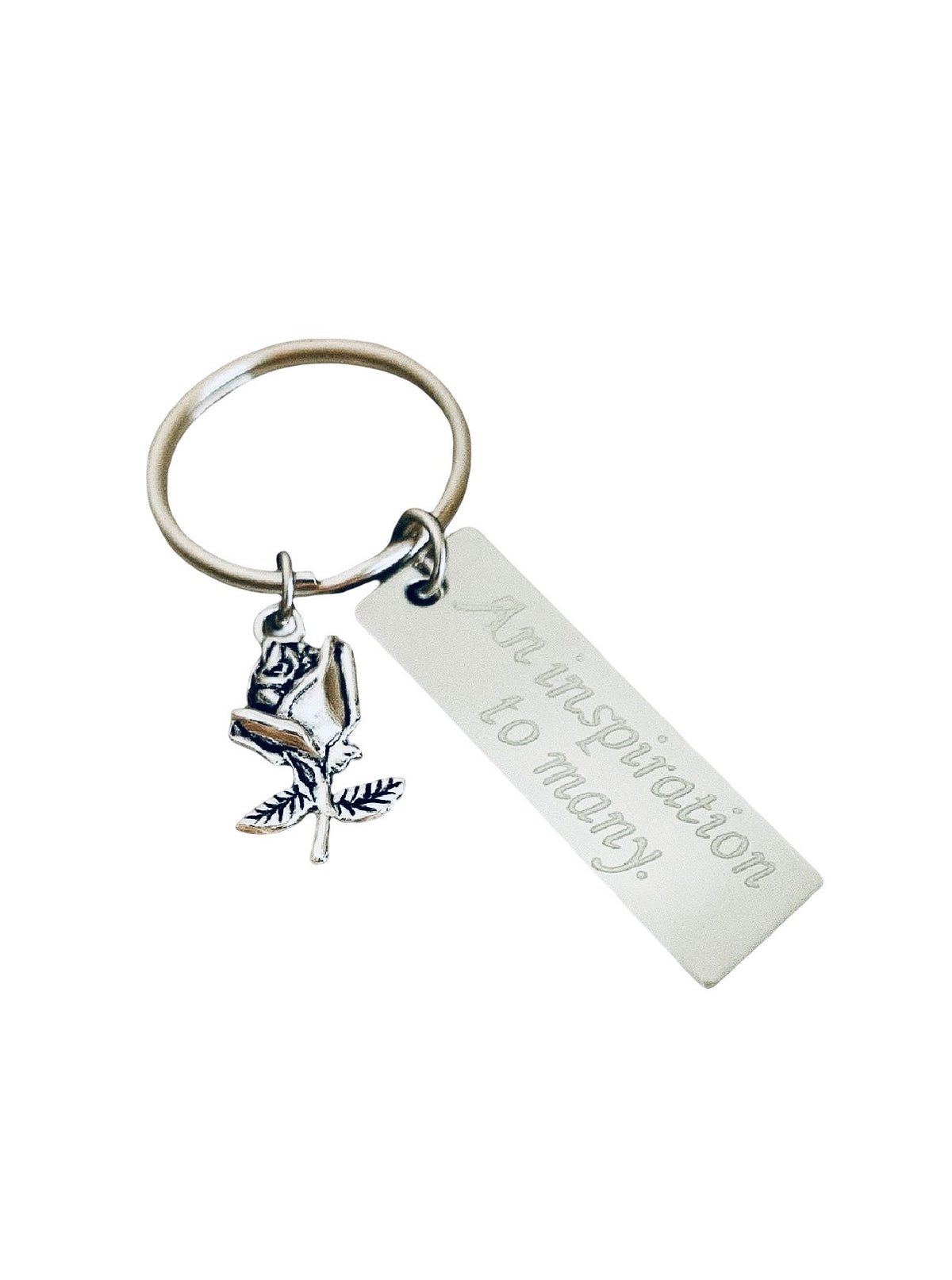 A silver-toned metal keychain featuring a rectangular engraved tag that reads 'An inspiration to many' and a small rose charm, shown on a plain white background.
