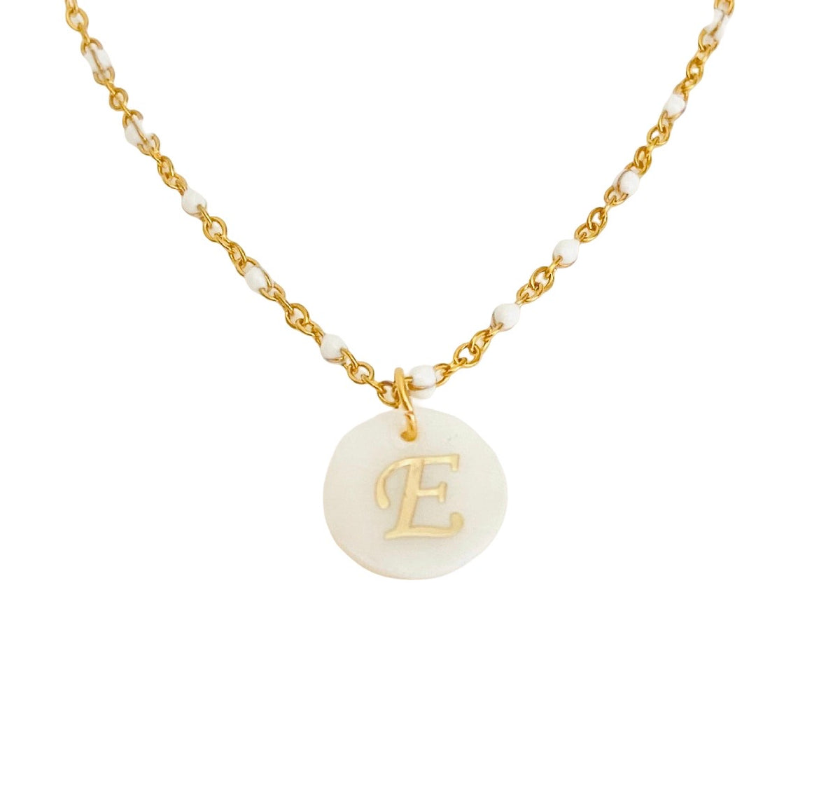 A gold chain necklace featuring small white beads and a round white disc pendant engraved with a gold initial 'E', shown on a plain white background.