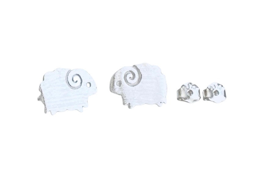 A pair of small white sheep-shaped stud earrings with silver spiral horns, shown next to two matching silver post backings on a plain white background.