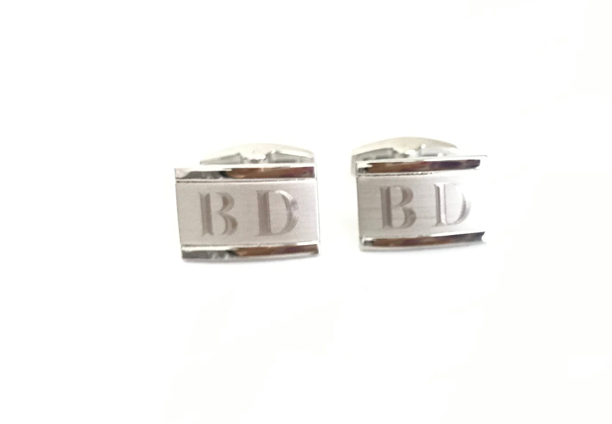 Silver cufflinks with 'BD' initials on a white background