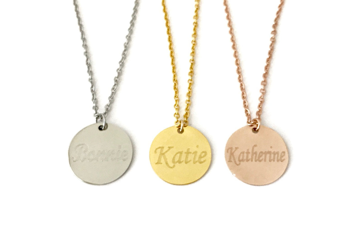Three necklaces with engraved names on round pendants against a white background