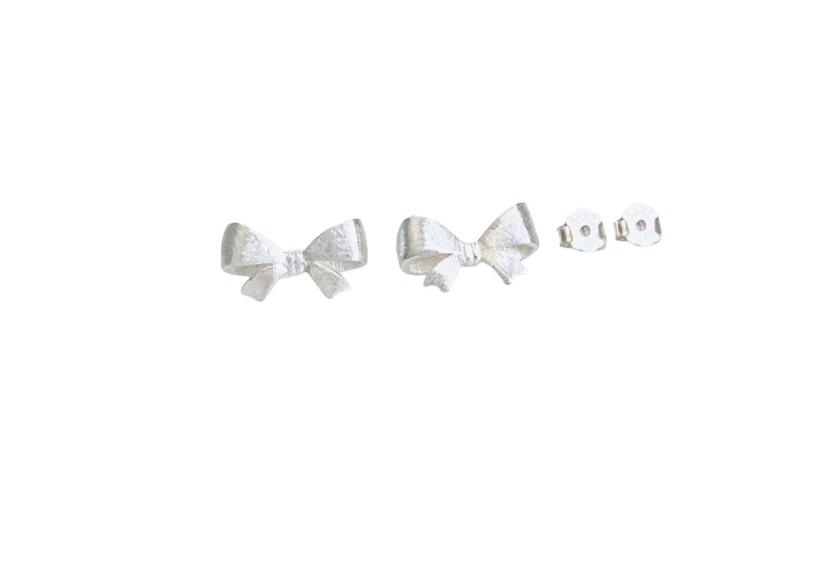 A pair of silver bow stud earrings with a textured finish, shown alongside their silver butterfly backing clips on a plain white background.