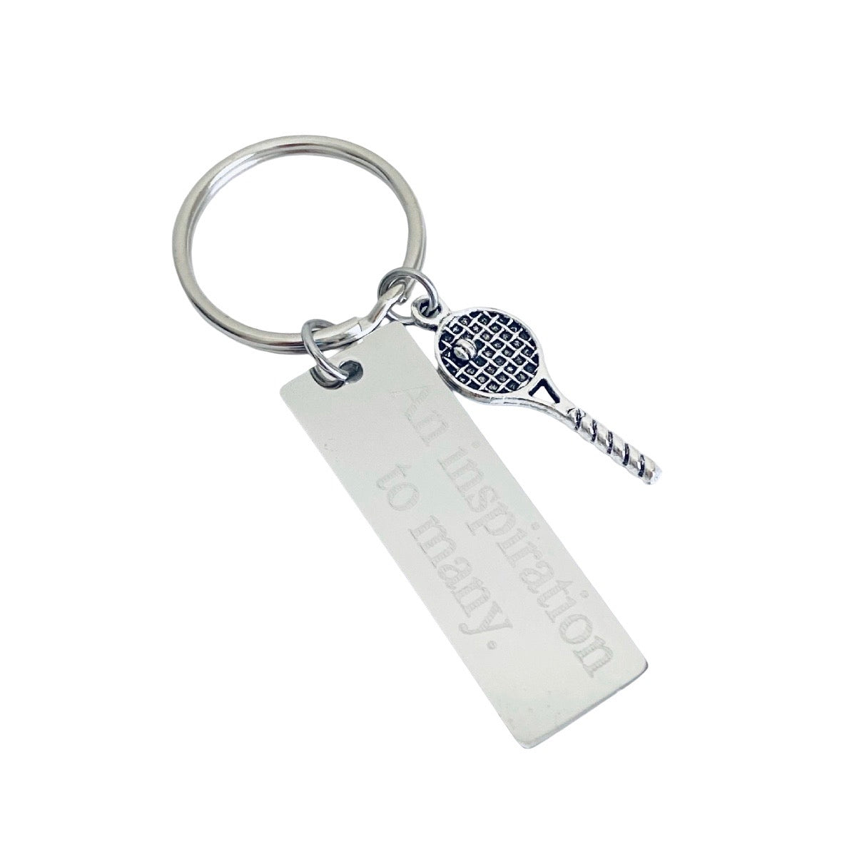 A silver metal keychain featuring a rectangular engraved tag that reads 'to inspiration to mary.' and a small tennis racket charm with a blue and white patterned head, shown on a plain white background.