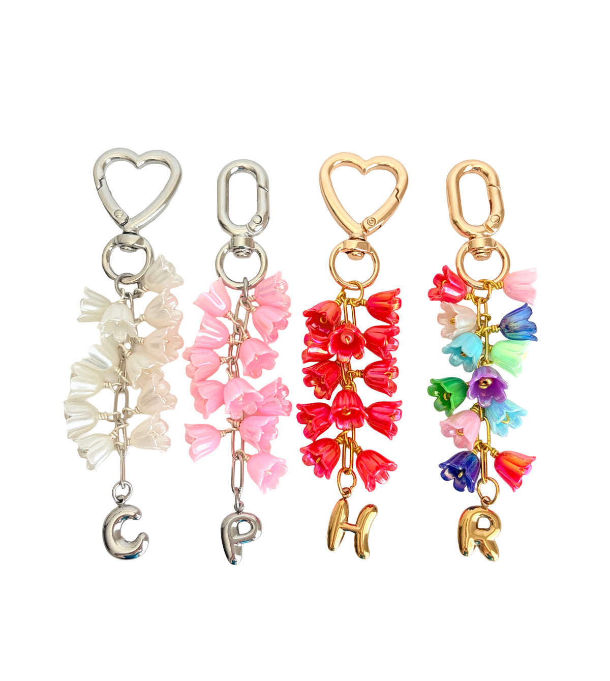 Four floral keychains with heart and letter charms on a white background