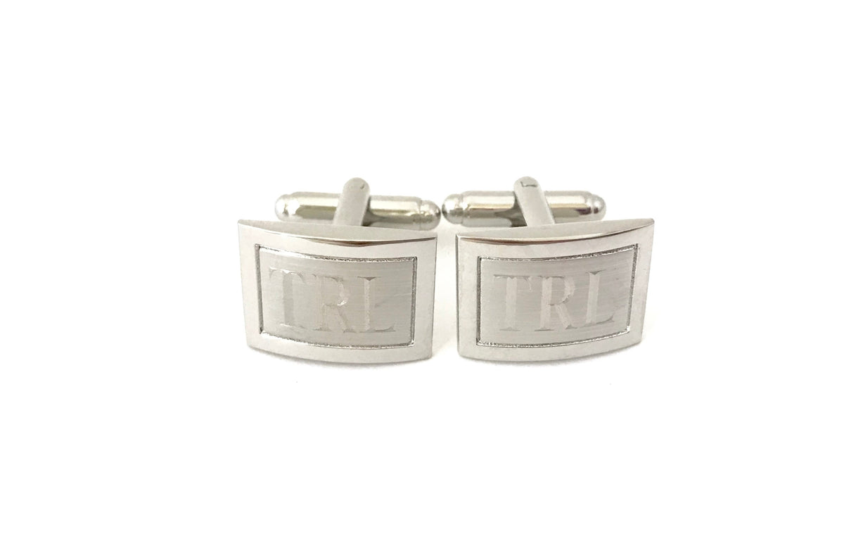 Silver cufflinks with 'TRL' engraving on a white background