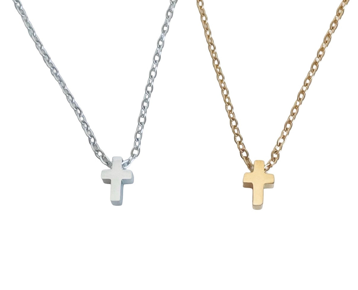 Two small cross pendant necklaces on chains, one silver-toned and one gold-toned, displayed against a plain white background.